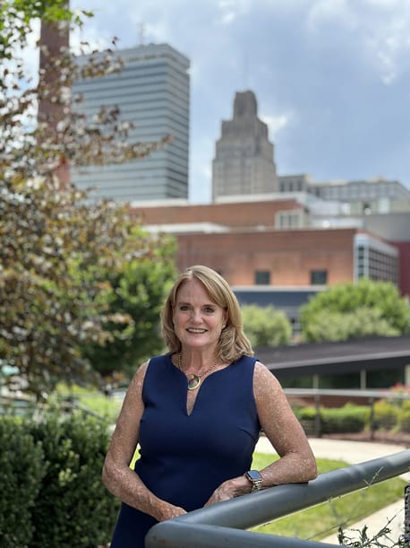 woman in a blue dress standing in front of a city skyline